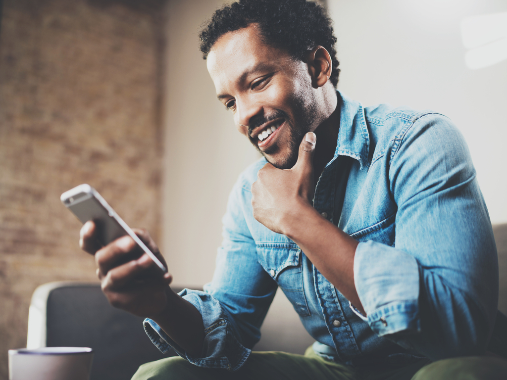 Businessman using phone while sitting on sofa at his modern home.